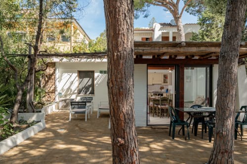 Shaded terrace with tall trees at Short Let's Olbia, featuring dining table and lounge seating