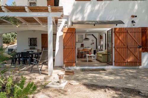 Mediterranean villa with open terrace, rustic wooden doors, and furnished patio at Short Let's Olbia