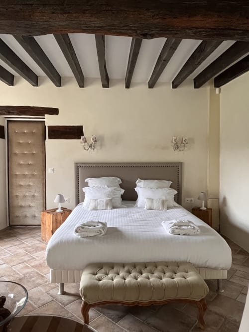 Chambre Le Manoir au Colombier de Hanches avec poutres apparentes, tête de lit grise et linge blanc