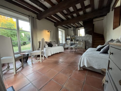 Chambre spacieuse au gîte Le Colombier de Hanches avec carrelage en terre cuite, poutres apparentes et vue sur le jardin