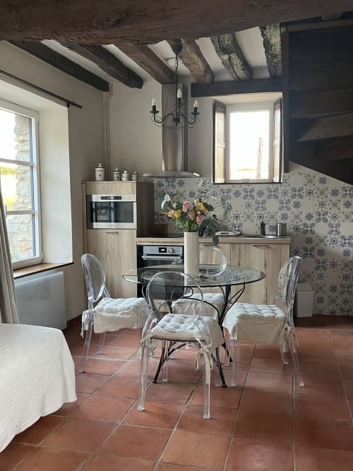 Cuisine-salle à manger moderne au gîte Le Colombier de Hanches avec chaises transparentes, table ronde et décor patterné