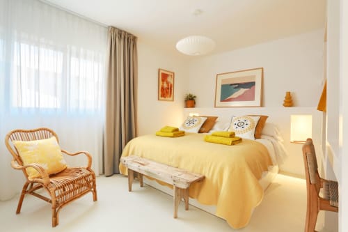 Habitación amarillo brillante en El Patrón Casa de Huéspedes de El Cotillo con silla de ratán, cama de madera y decoración costera