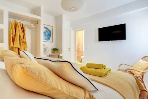 Dormitorio luminoso en El Patrón Casa de Huéspedes en El Cotillo con ropa de cama amarilla, TV mural y comodidades modernas