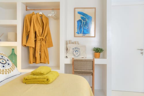 Dormitorio luminoso en El Patrón Casa de Huéspedes, El Cotillo, con ropa de cama amarilla, albornoz mostaza, arte azul y blanco