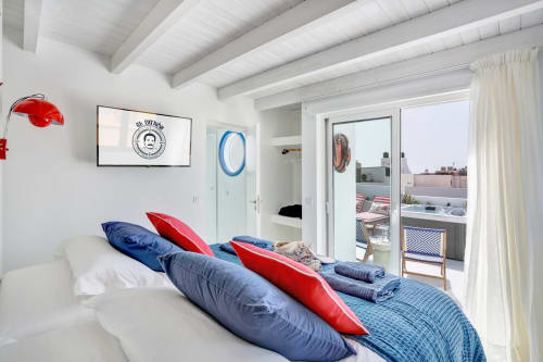 Dormitorio luminoso en El Patrón Casa de Huéspedes en El Cotillo con cojines azules y rojos, vigas vistas y terraza con vista al mar