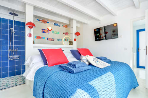 Luminosa habitación en El Patrón Casa de Huéspedes con ropa de cama azul, almohadas rojas y decoración náutica en El Cotillo