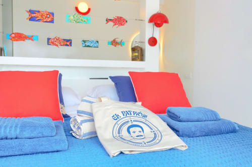 Habitación colorida en El Patrón Casa de Huéspedes, El Cotillo, con ropa de cama azul, almohadas rojas y decoraciones náuticas