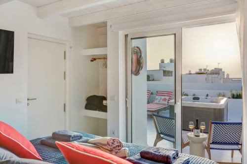 Dormitorio luminoso en El Patrón Casa de Huéspedes, El Cotillo, con vistas al mar, detalles rojos y acceso a terraza.