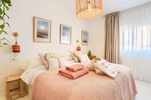 Luminosa habitación de El Patrón Casa de Huéspedes en El Cotillo con ropa de cama rosa, detalles de madera y luz natural