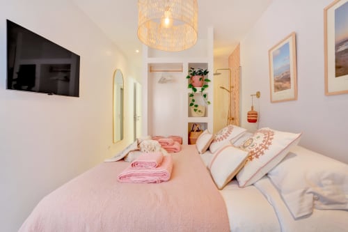Dormitorio luminoso en El Patrón Casa de Huéspedes, El Cotillo: cama rosa, lámpara de techo tejida y cuadros enmarcados