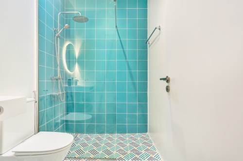 Cuarto de baño moderno en El Patrón Casa de Huéspedes con ducha de azulejos turquesas, cabezal tipo lluvia y piso geométrico