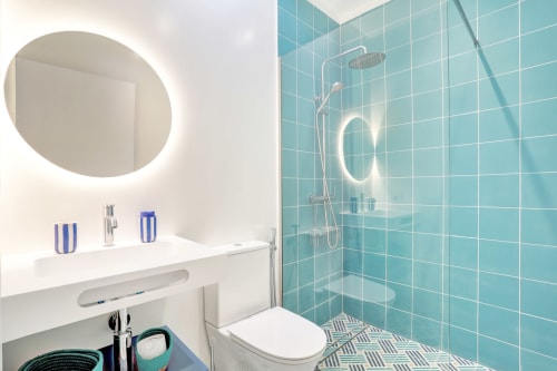 Baño moderno en El Patrón Casa de Huéspedes, El Cotillo con azulejos turquesa, espejo circular y ducha abierta