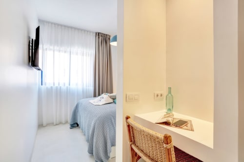 Habitación luminosa en El Patrón Casa de Huéspedes en El Cotillo con escritorio, cama y ventana con cortinas