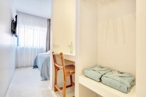 Dormitorio luminoso en El Patrón Casa de Huéspedes, El Cotillo, con cama, escritorio, silla y ropa de cama doblada en estante