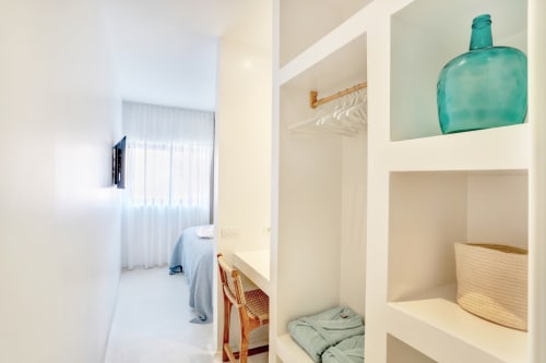 Habitación luminosa en El Patrón Casa de Huéspedes, El Cotillo, con estanterías integradas, decoración turquesa y diseño minimalista moderno