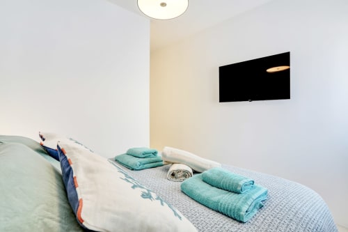 Habitación en El Patrón Casa de Huéspedes en El Cotillo con cama, toallas enrolladas y TV de pared