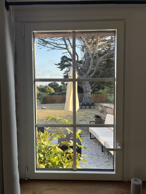 Vue du Gîte du Cap Fréhel : terrasse de jardin avec arbre centenaire, coin détente et paysage côtier de Plévenon