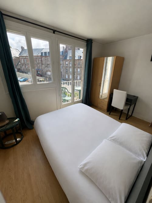 Chambre double lumineuse à l'Hôtel bistrot de la poste avec literie blanche, armoire en bois, bureau et balcon donnant sur la cour