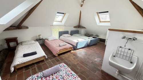 Spacious attic bedroom at Le Gite De Saint Phal with multiple beds, skylights, exposed beams, and sink in Saint-Phal