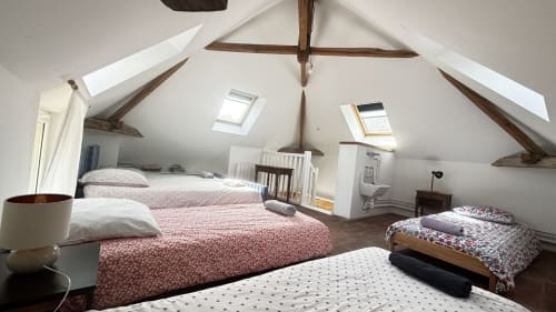 Spacious attic bedroom at Le Gite De Saint Phal cottage with multiple beds, exposed beams, skylights, and garden views