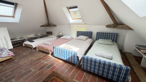 Attic bedroom at Le Gite De Saint Phal with multiple beds, blue plaid bedding, exposed beams, and skylights
