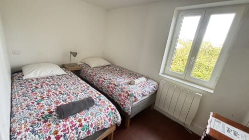 Twin bedroom in Le Fournil cottage at Le Gite De Saint Phal with garden view, white walls, and floral bedding