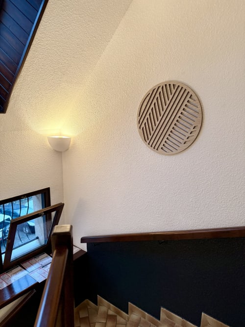Détail de chambre à l'Hôtel le tilleul : murs crème, œuvre d'art circulaire géométrique et applique murale moderne