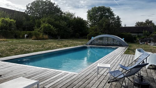 Le Gite De Saint Phal's heated pool with retractable cover, wooden deck, and lounge chairs in Saint-Phal, France