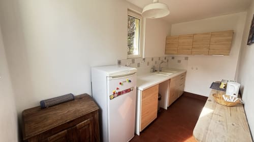Kitchen area with wooden cabinets, white appliances, and tiled backsplash at Le Gite De Saint Phal