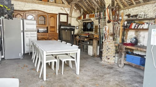 Converted barn studio at Le Gite De Saint Phal with white dining table, exposed beams, brick chimney, and rustic furnishings