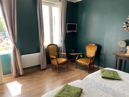 Elegant bedroom at Au Bois Dormant with teal walls, gold armchairs, and garden views in Hesdin-la-Forêt
