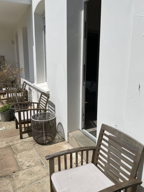 Au Bois Dormant terrace with wooden chairs, woven table, and white building entrance in Hesdin-la-Forêt
