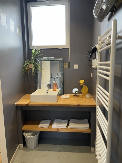 Modern bathroom in Chambre Bleu at Au Bois Dormant B&B, featuring white vessel sink, wooden countertop, heated towel rack,