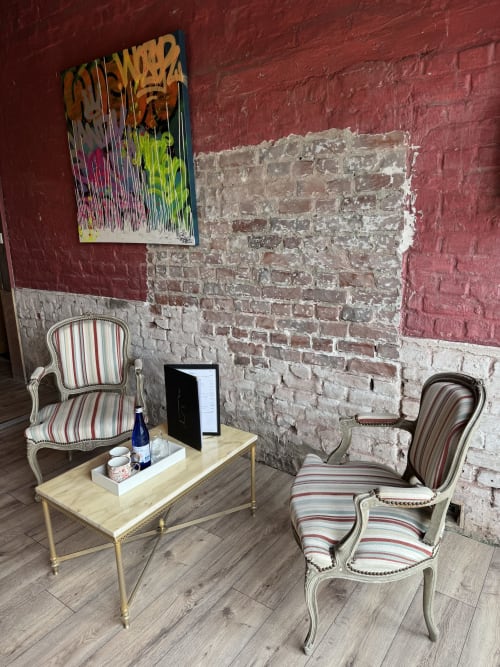 Retro room at Au Bois Dormant with striped armchairs, wooden table, exposed brick wall, and colorful artwork in