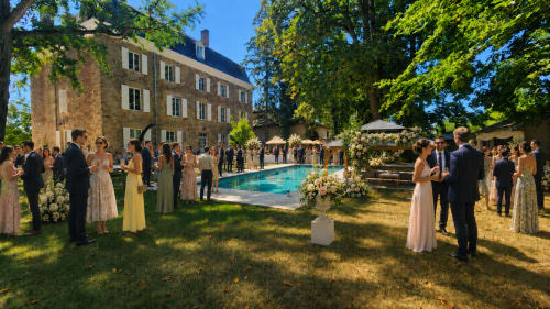 Réception de mariage au Château de la Rochetière à Marcilloles, France, avec les invités près de la piscine et le manoir historique en pierre.