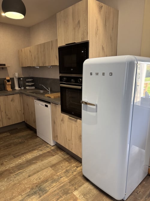 Modern kitchen in Suite Magnolia cottage at Au Bois Dormant with white SMEG fridge, wooden cabinets, and stainless steel