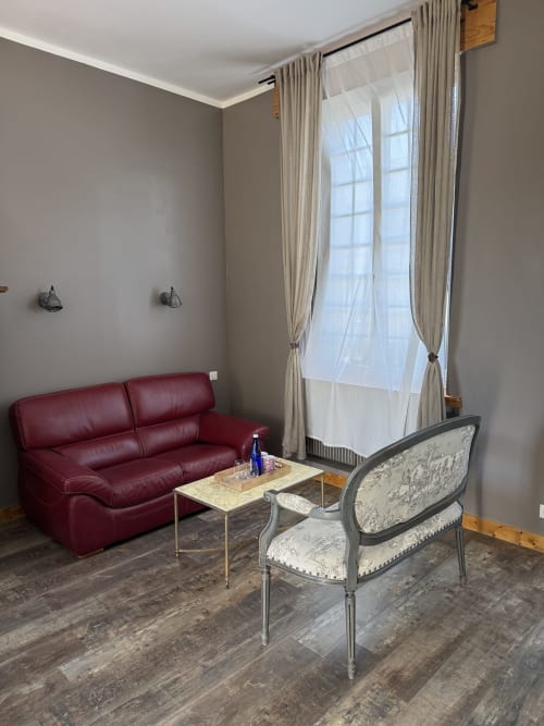 Suite Magnolia living area at Au Bois Dormant with burgundy sofa, upholstered chair, and garden views in Hesdin-la-Forêt