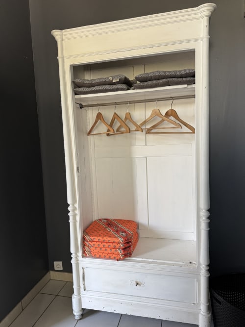 White wardrobe with wooden hangers and folded linens in Suite Magnolia cottage at Au Bois Dormant, Hesdin-la-Forêt