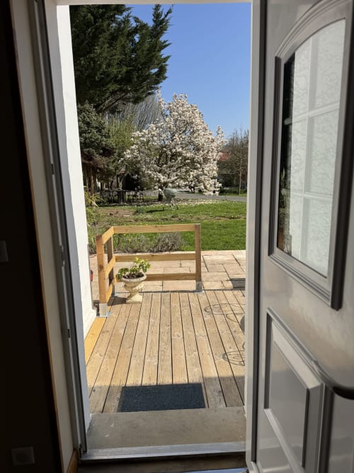 Garden view from Suite Magnolia cottage at Au Bois Dormant in Hesdin-la-Forêt, showing wooden deck, blooming magnolia trees