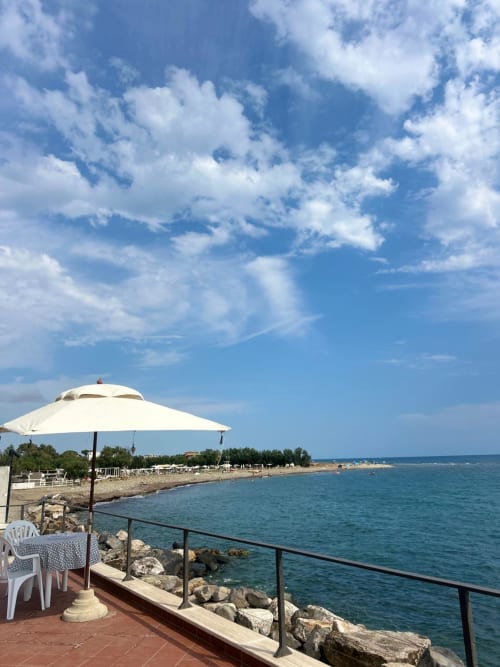 Terrazza affacciata sul mare della villa Casa Bella Pantheon a Santa Marinella con ombrellone bianco, vista mare e accesso diretto alla spiaggia