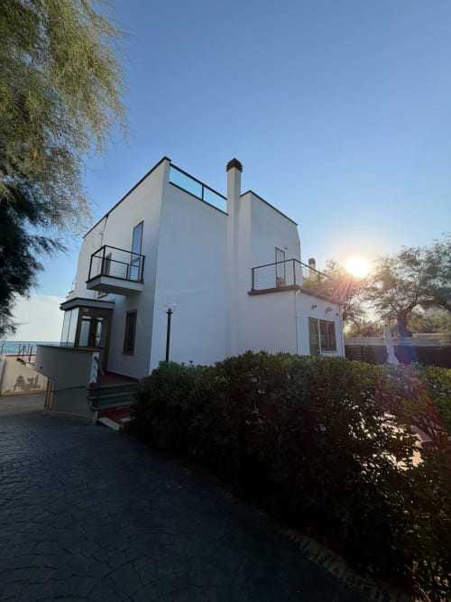 Villa bianca moderna a Casa Bella Pantheon, Santa Marinella con vista mare, balconi e giardino paesaggistico al tramonto