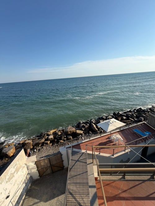 Terrazza Villa Mareluce affacciata sul Mar Tirreno a Santa Marinella con lettini e scogliera frangiflutti
