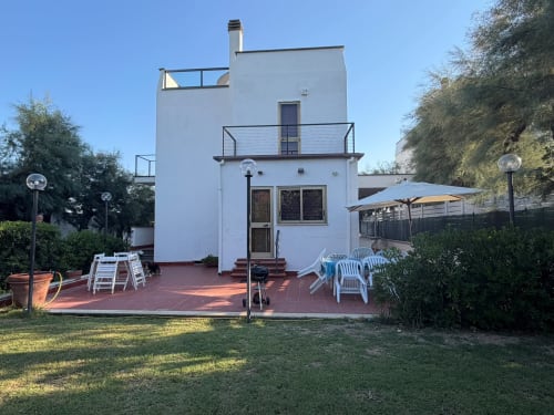 Villa Mareluce presso Casa Bella Pantheon, Santa Marinella. Moderna villa bianca con terrazza, sedie blu, ombrellone e vista sul mare