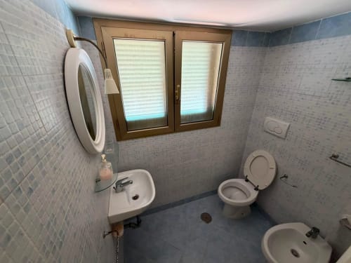 Bagno con più lavandini, toilette e finestra con cornice in legno nella villa Casa Bella Pantheon a Santa Marinella, Italia
