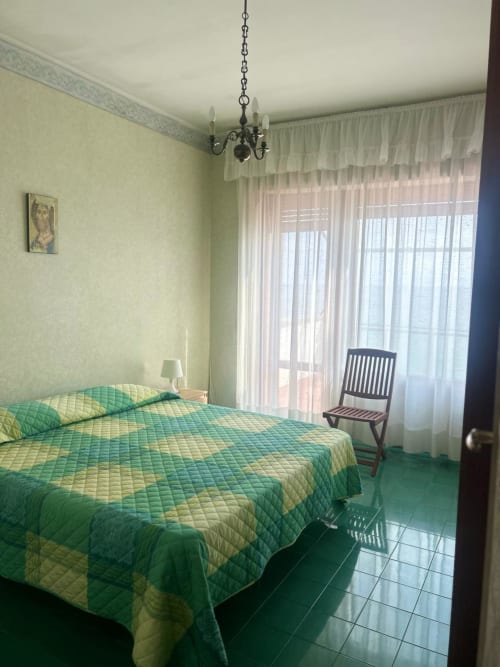Camera da letto luminosa nella villa Casa Bella Pantheon a Santa Marinella con biancheria trapuntata verde, vista sul mare e elegante lampadario