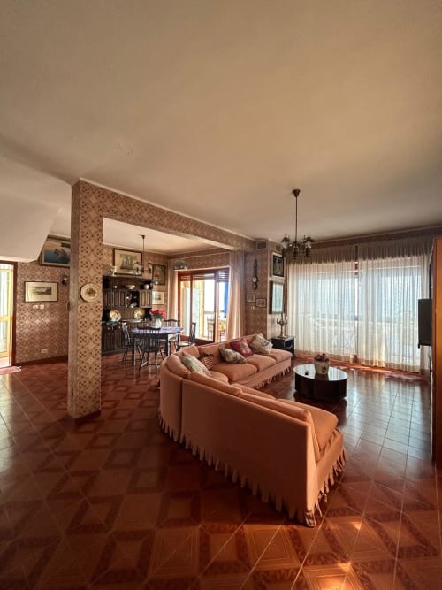 Ampio soggiorno della villa Casa Bella Pantheon con pavimenti in terracotta, divano color corallo e vista sul mare a Santa Marinella