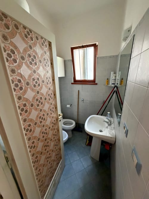 Bagno della villa Casa Bella Pantheon a Santa Marinella con lavandino, toilette, doccia e pareti piastrellate
