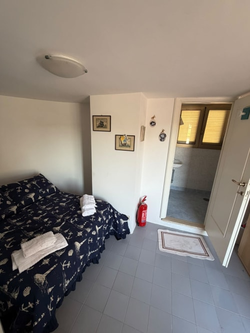 Camera della villa Casa Bella Pantheon a Santa Marinella con vista sul mare, letto con biancheria nautica, accesso bagno e stile moderno