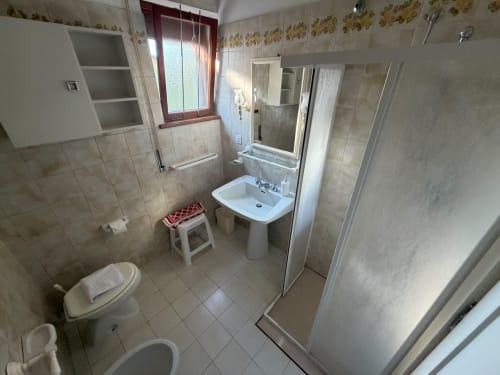 Ampio bagno della villa Casa Bella Pantheon a Santa Marinella con lavabo su piedistallo, doccia e toilette