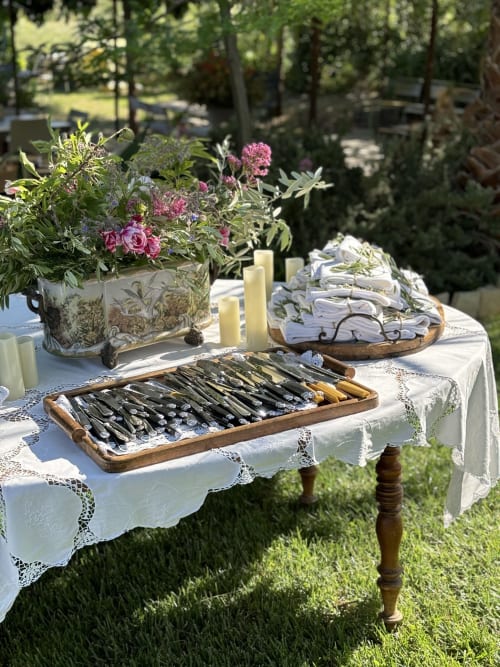 Élégante table dressée en terrasse au Clos Bb à Saint-Cyr sur Mer avec fleurs roses, chandeliers et couverts.